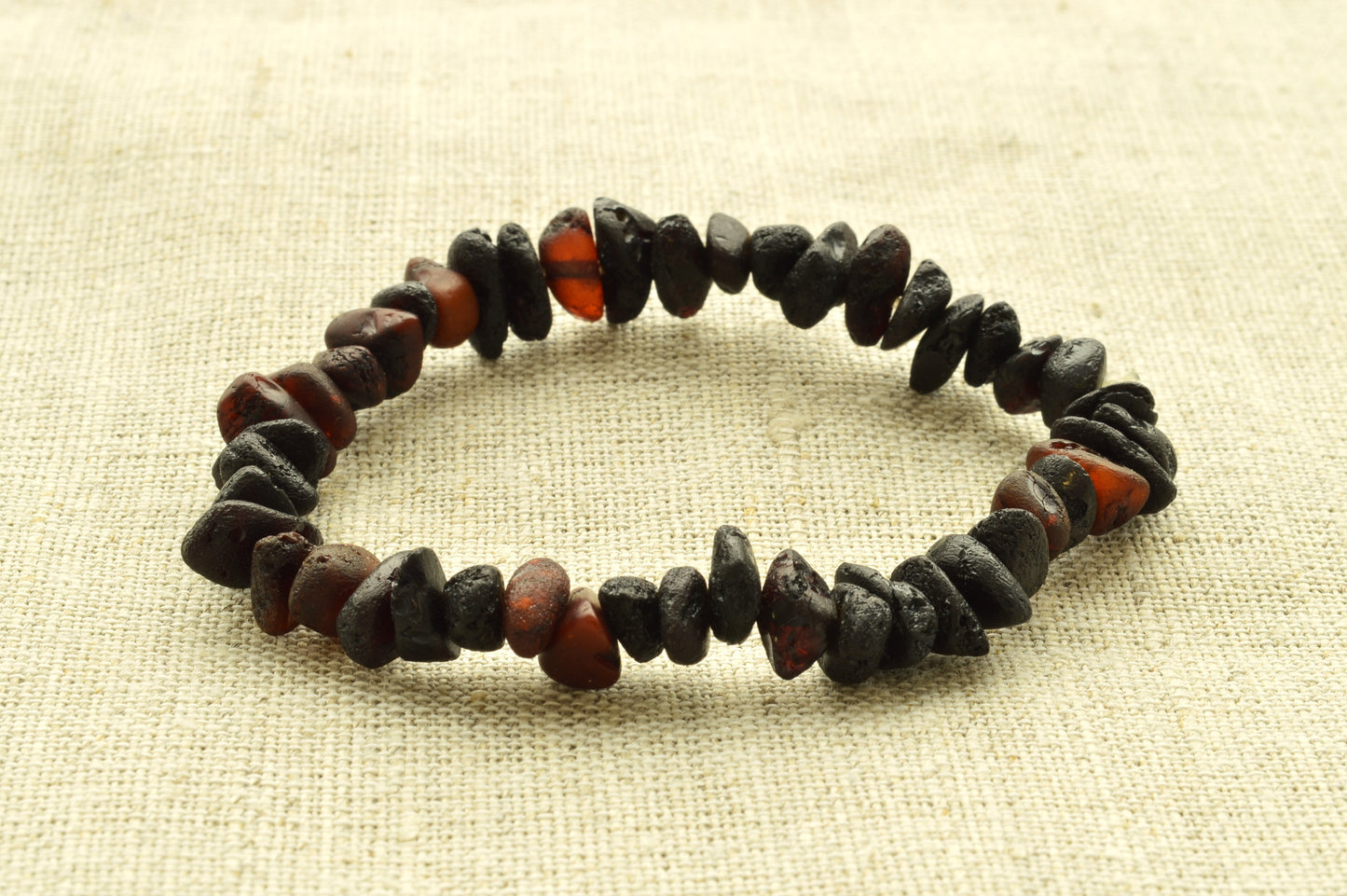Bracelet made of dark and red beads on a beige fabric background