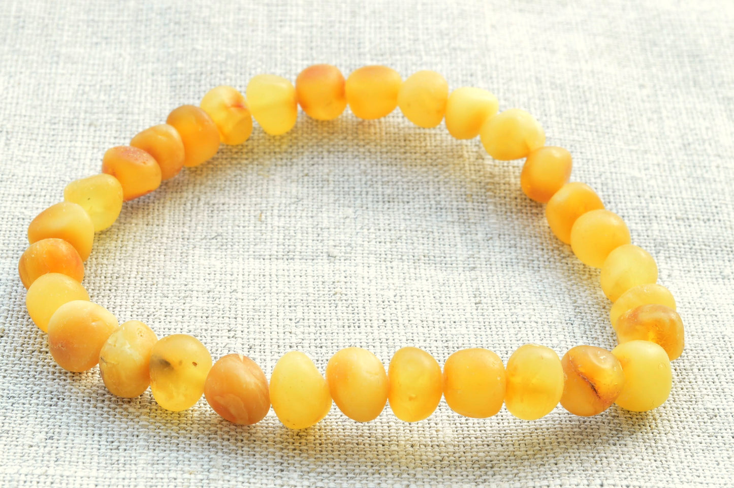 Yellow beaded bracelet on a textured fabric background
