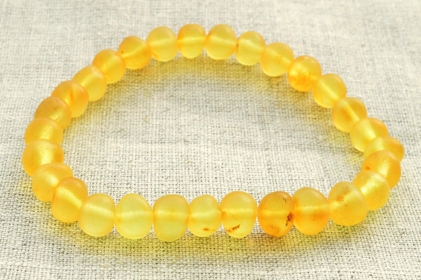 Yellow beaded bracelet on a textured fabric background