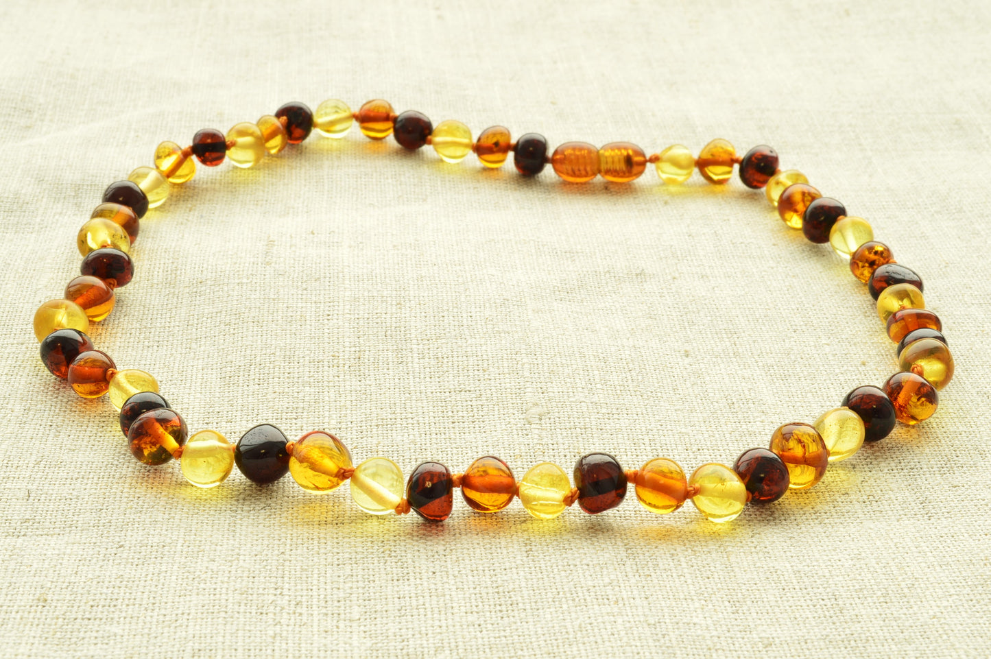 Beaded necklace with multicolored beads on a textured fabric background