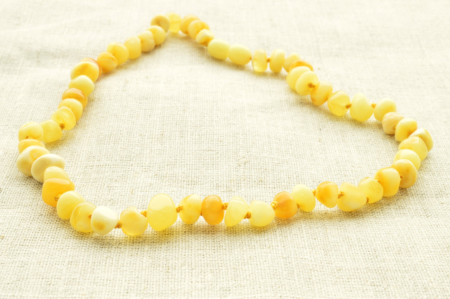 Yellow beaded necklace on a textured beige fabric background