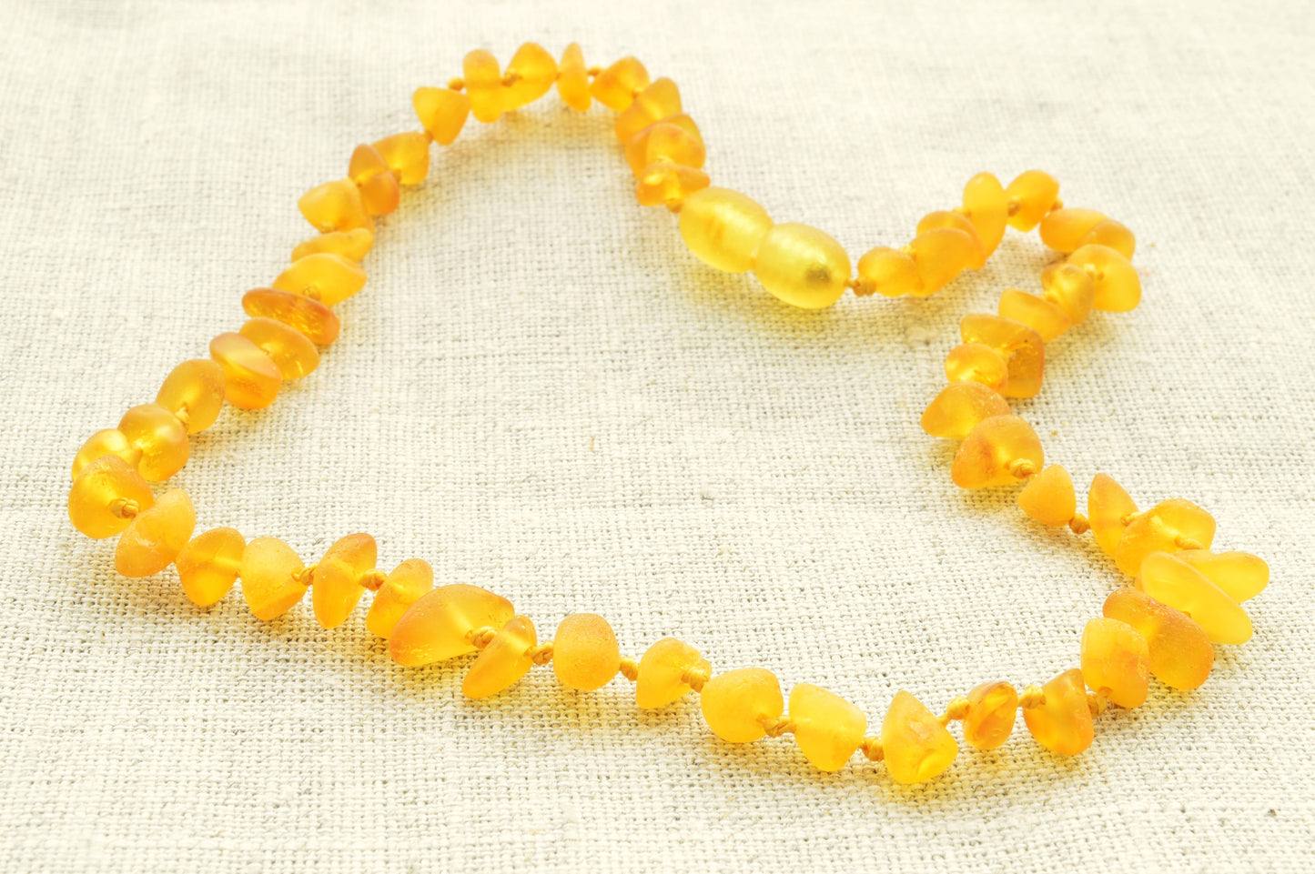 Yellow beaded necklace on a textured fabric background