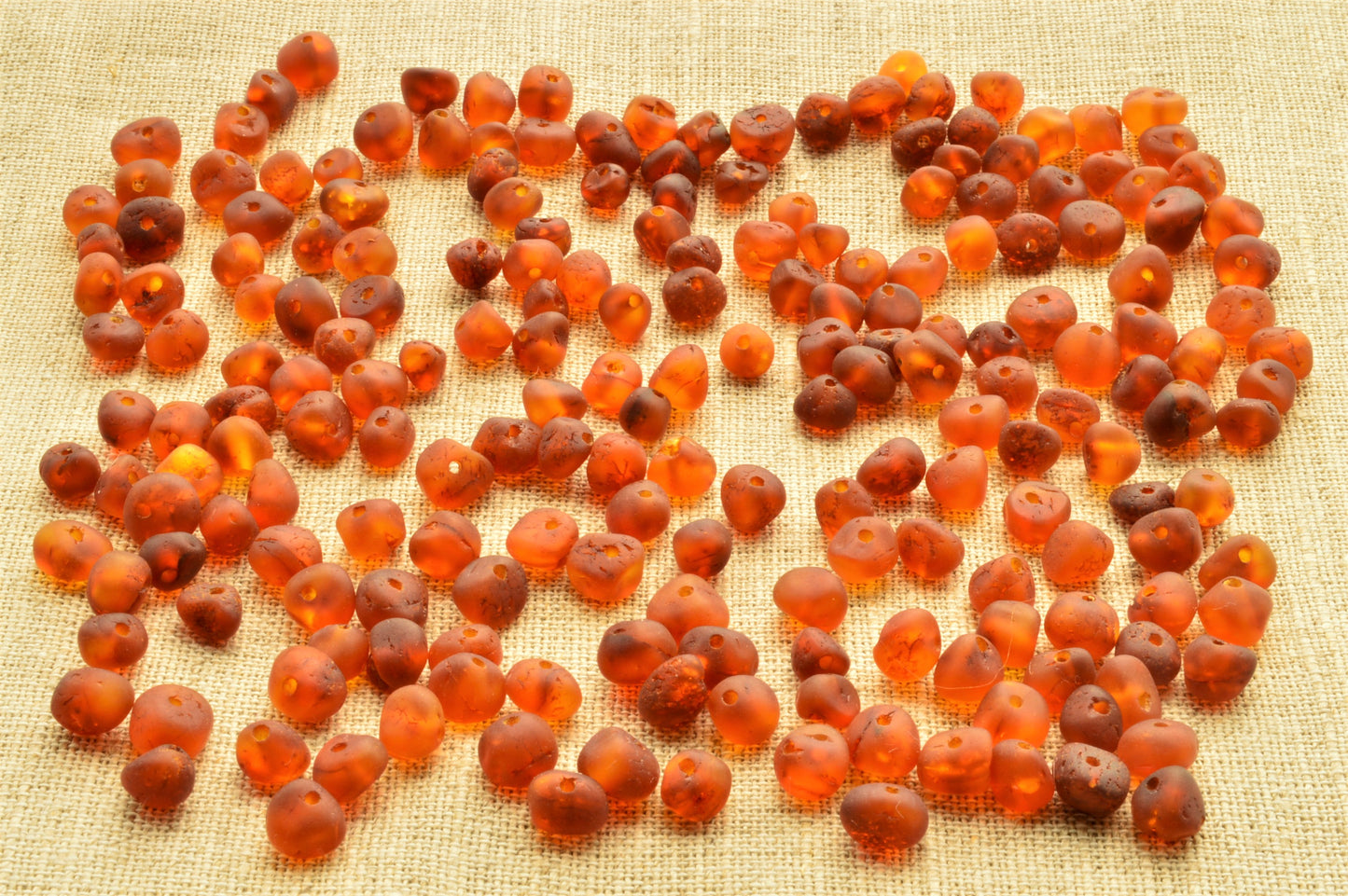 Close-up of amber-colored beads on a textured fabric background