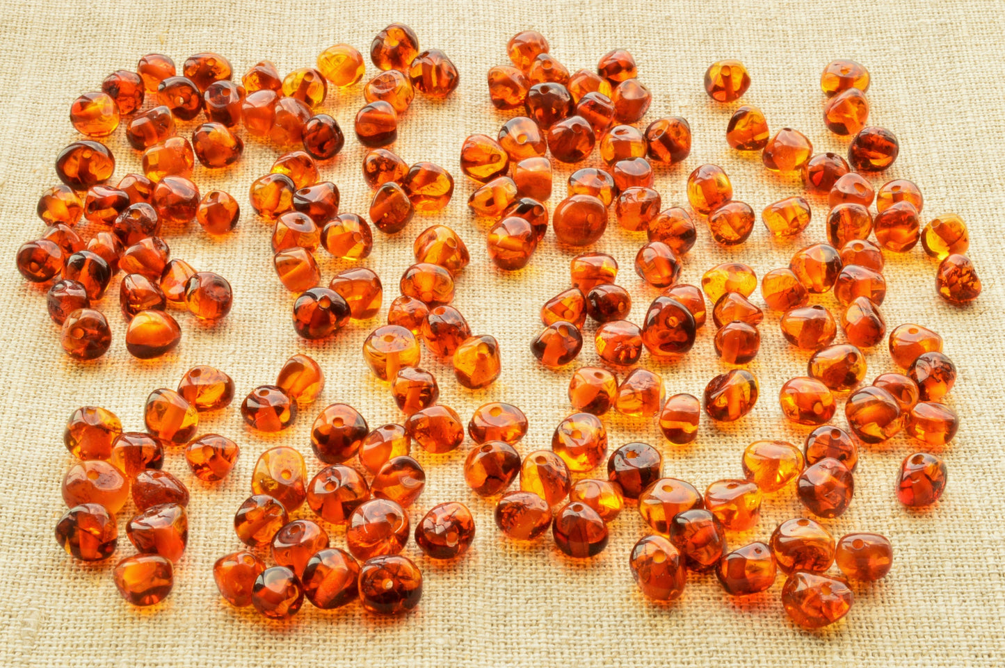 Amber-colored beads scattered on a textured fabric background