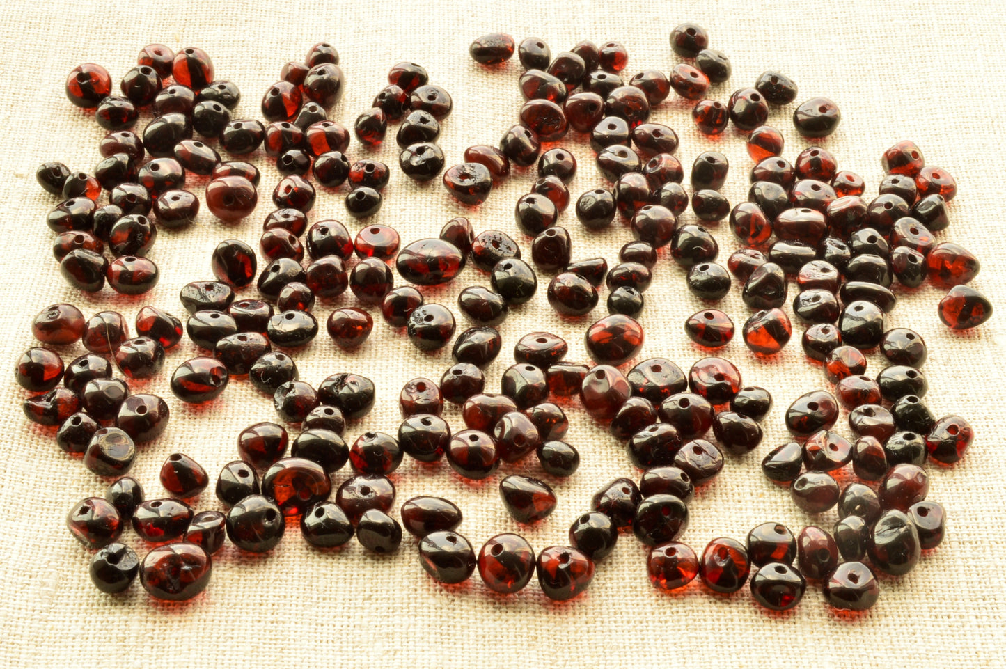 Dark red beads scattered on a textured surface