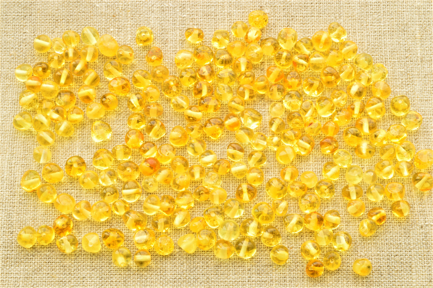 Yellow beads scattered on a textured beige fabric background