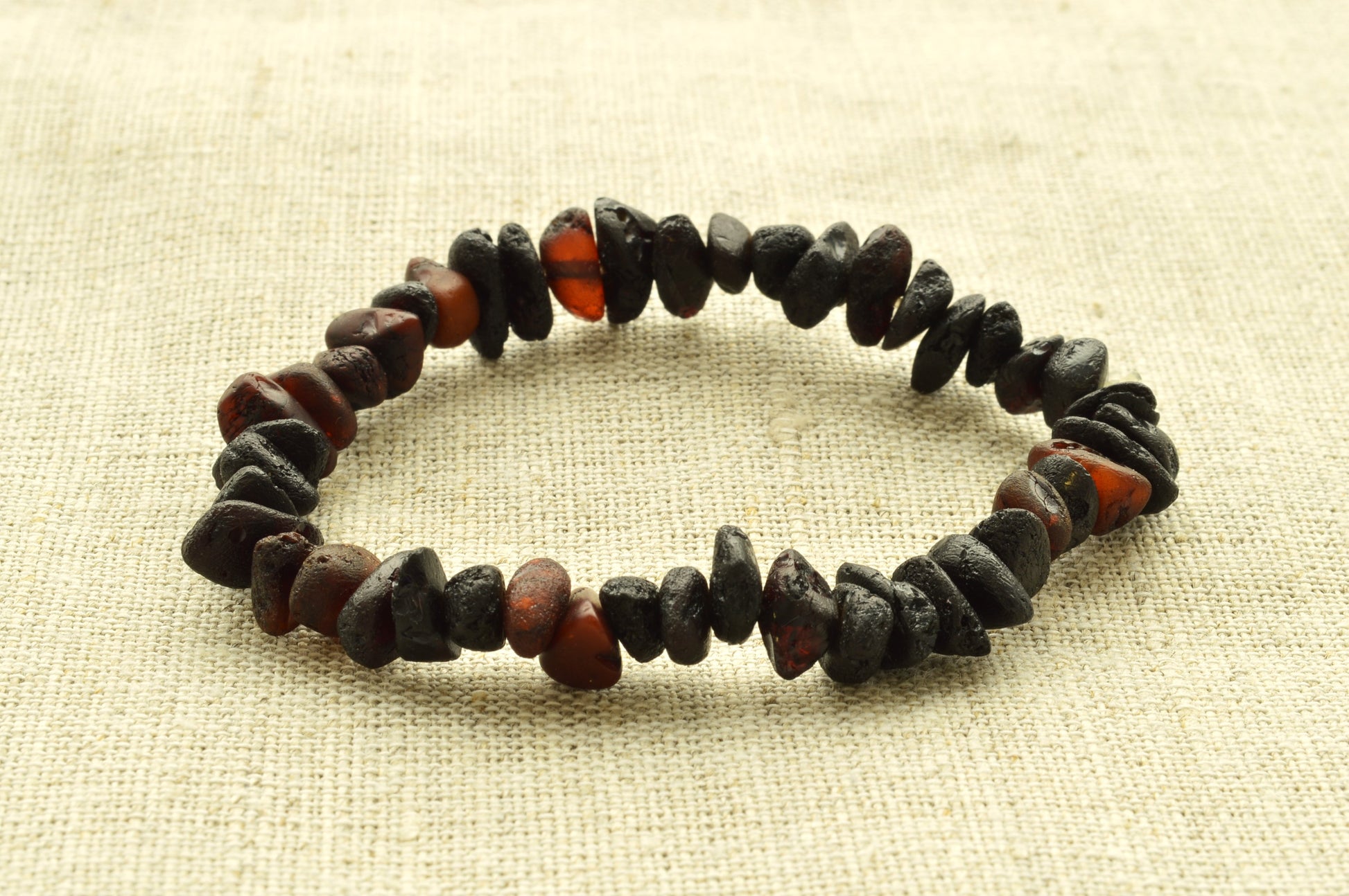 Bracelet made of dark and red beads on a beige fabric background
