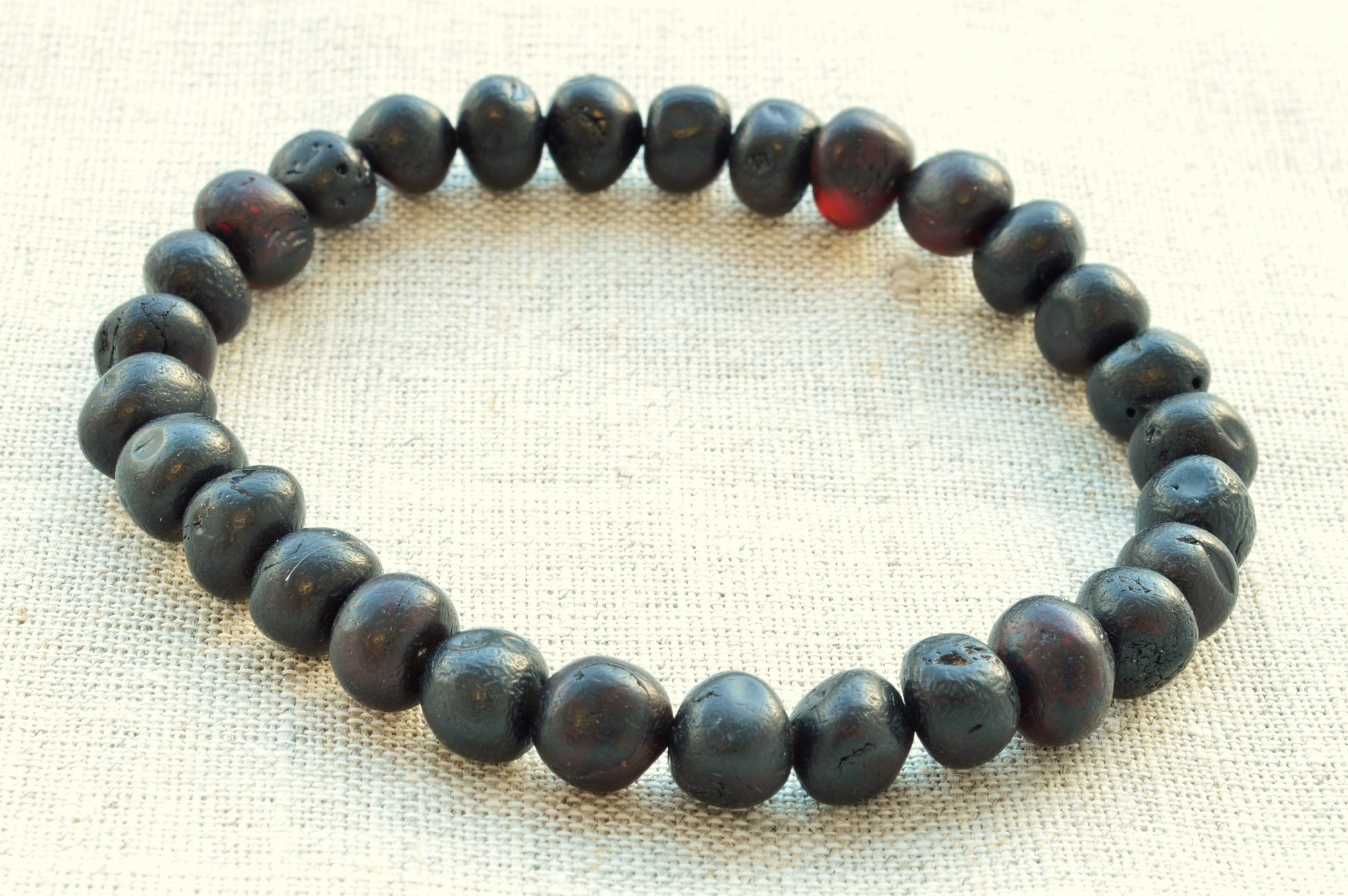 Black beaded bracelet on a textured beige background