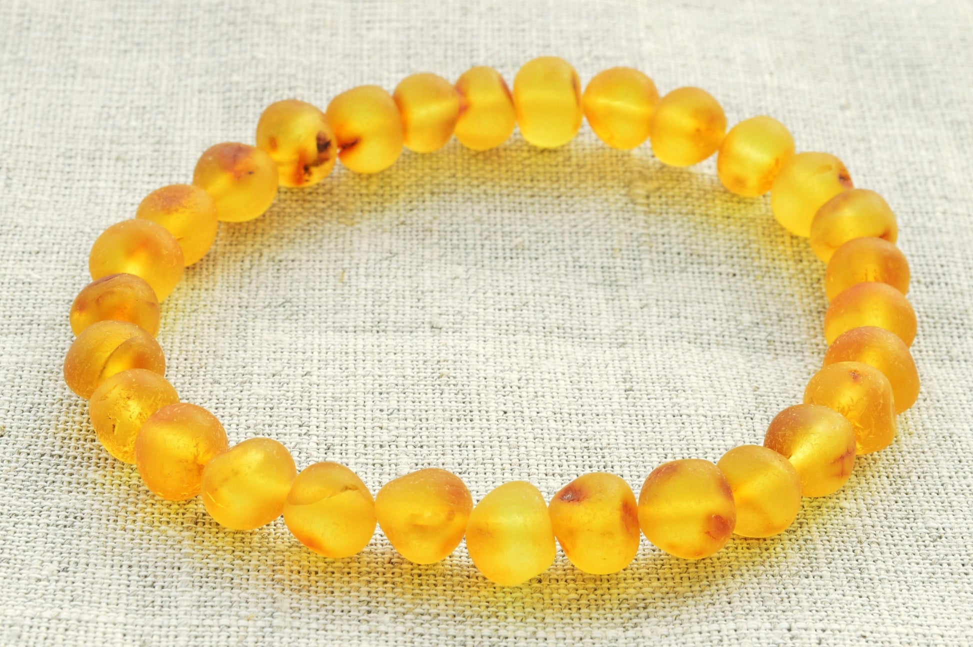 Yellow beaded bracelet on a textured fabric background