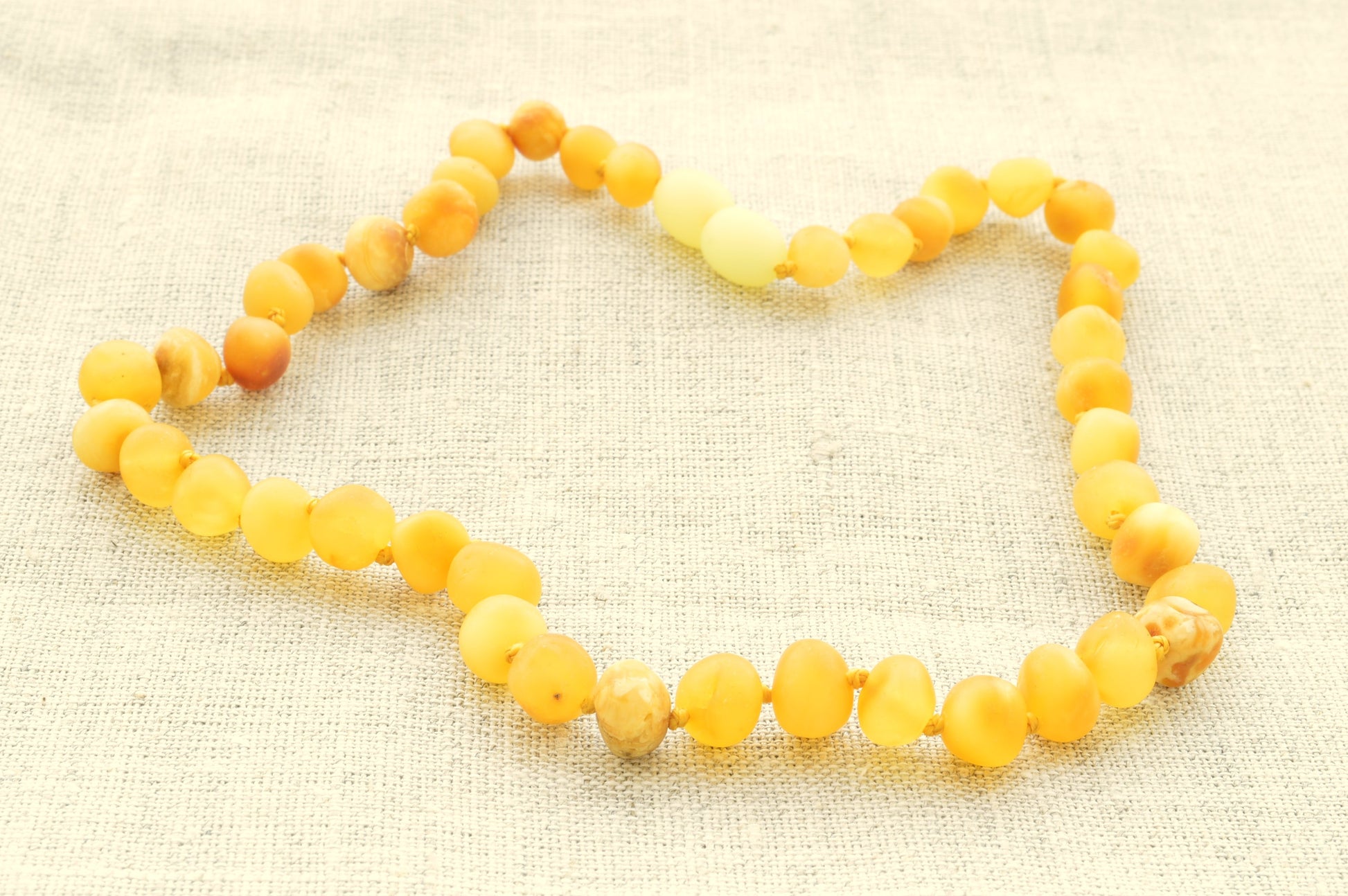 Yellow beaded necklace on a beige fabric background