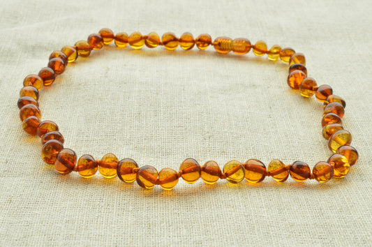 Amber teething necklace on a light fabric background