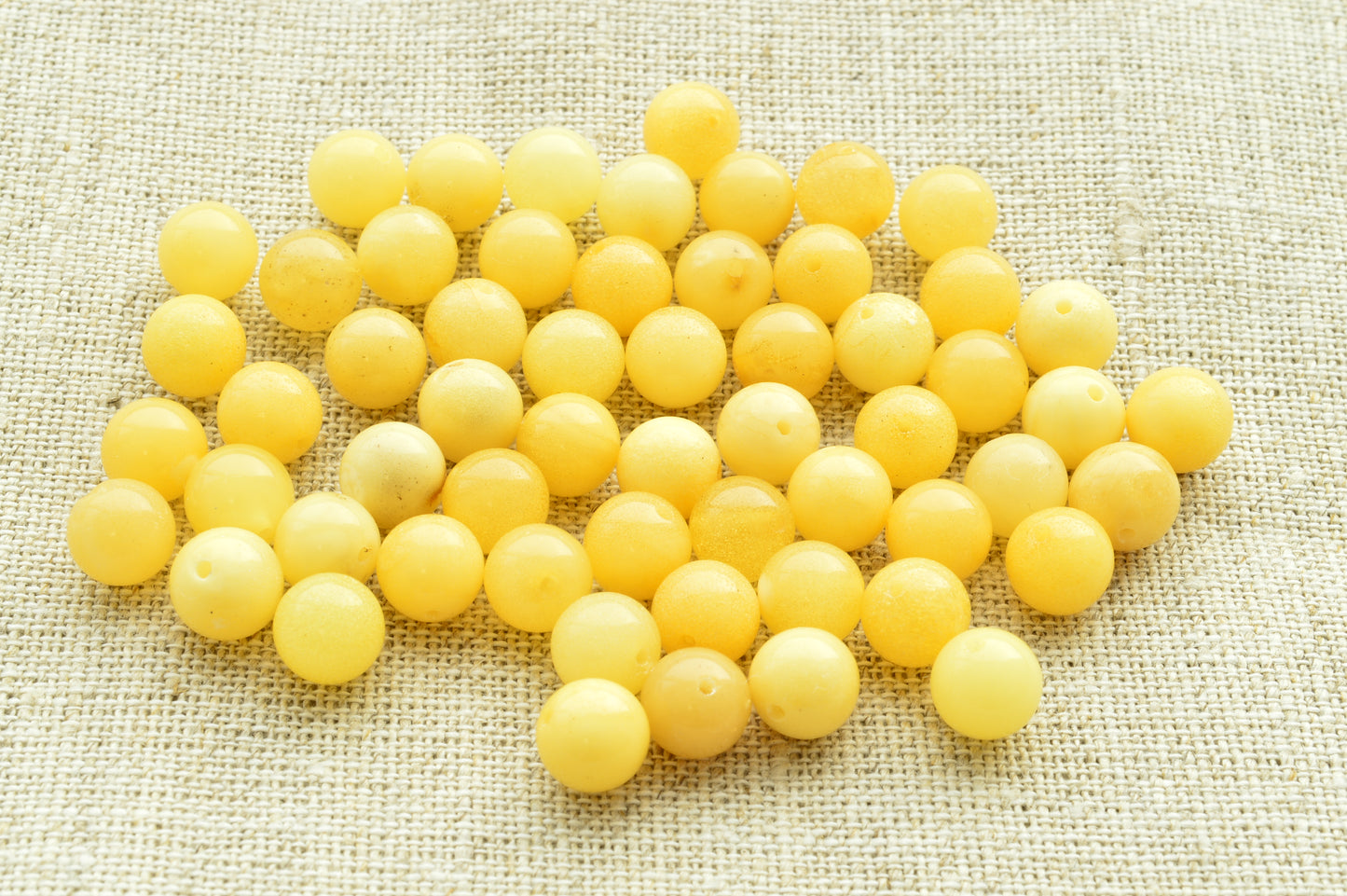 Natural baltic amber Yellow beads scattered on a textured beige fabric background