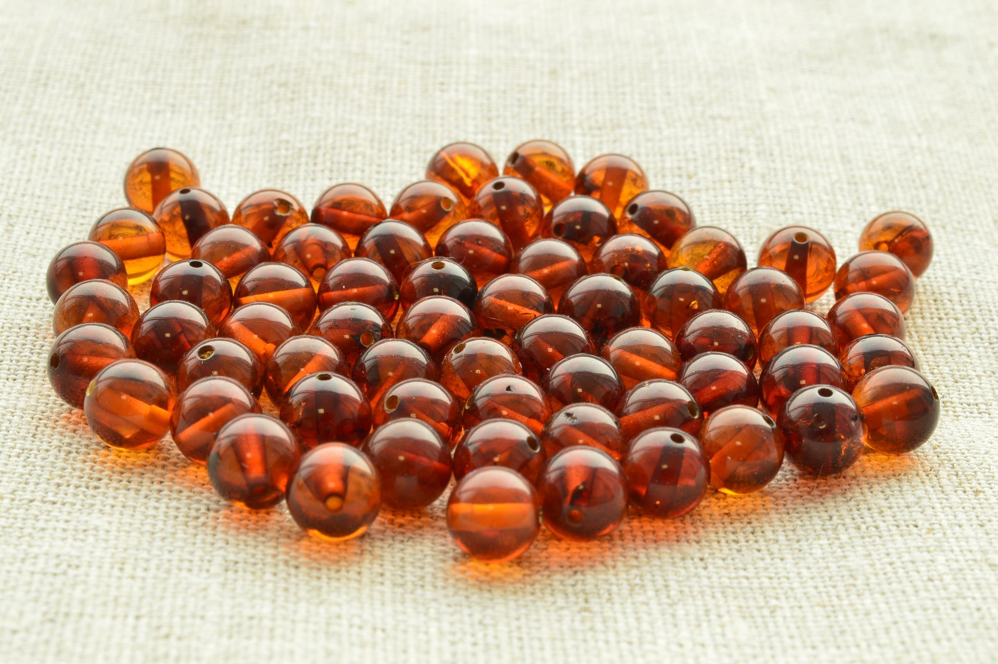 Natural baltic amber Brown beads on a textured beige fabric background