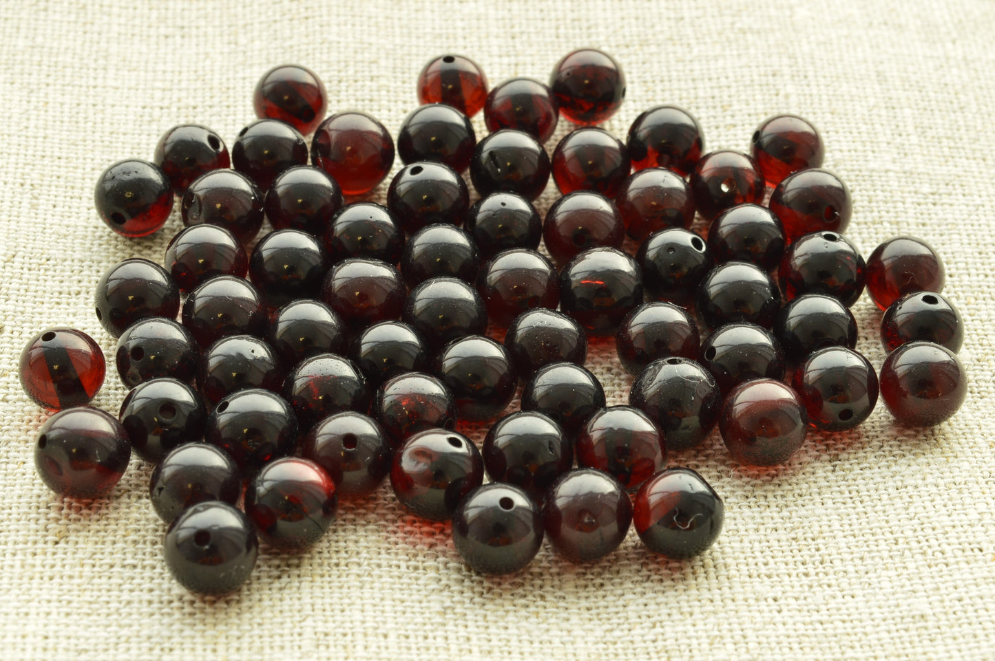 Natural baltic amber Collection of dark red amber beads on a textured fabric background
