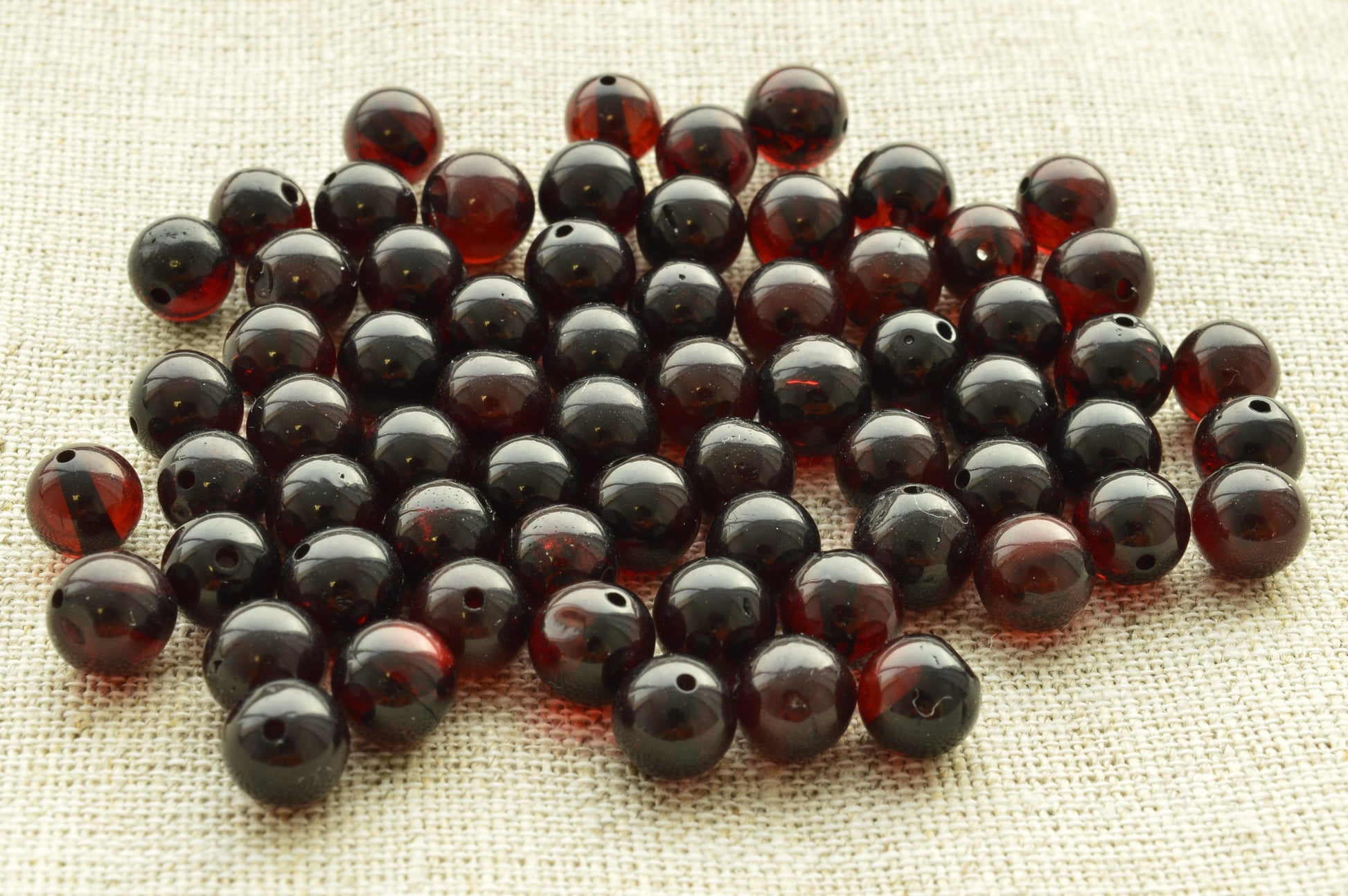 Natural baltic amber Collection of dark red amber beads on a textured fabric background