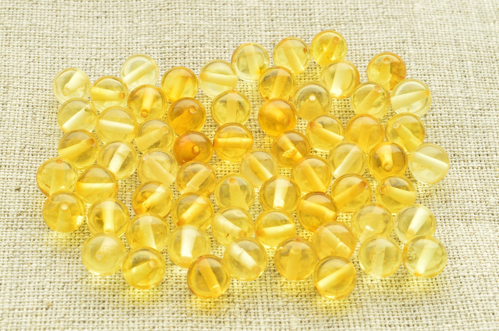 Natural baltic amber Yellow beads on a textured beige fabric background