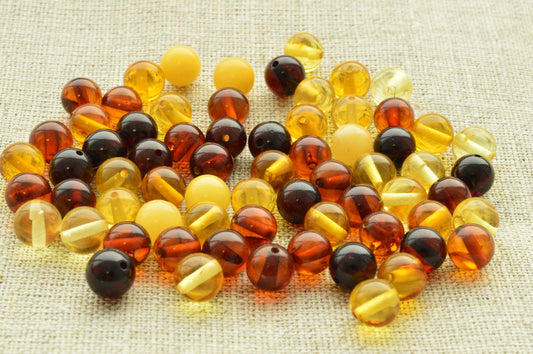 Natural baltic amber Multicolored round beads on a textured fabric background