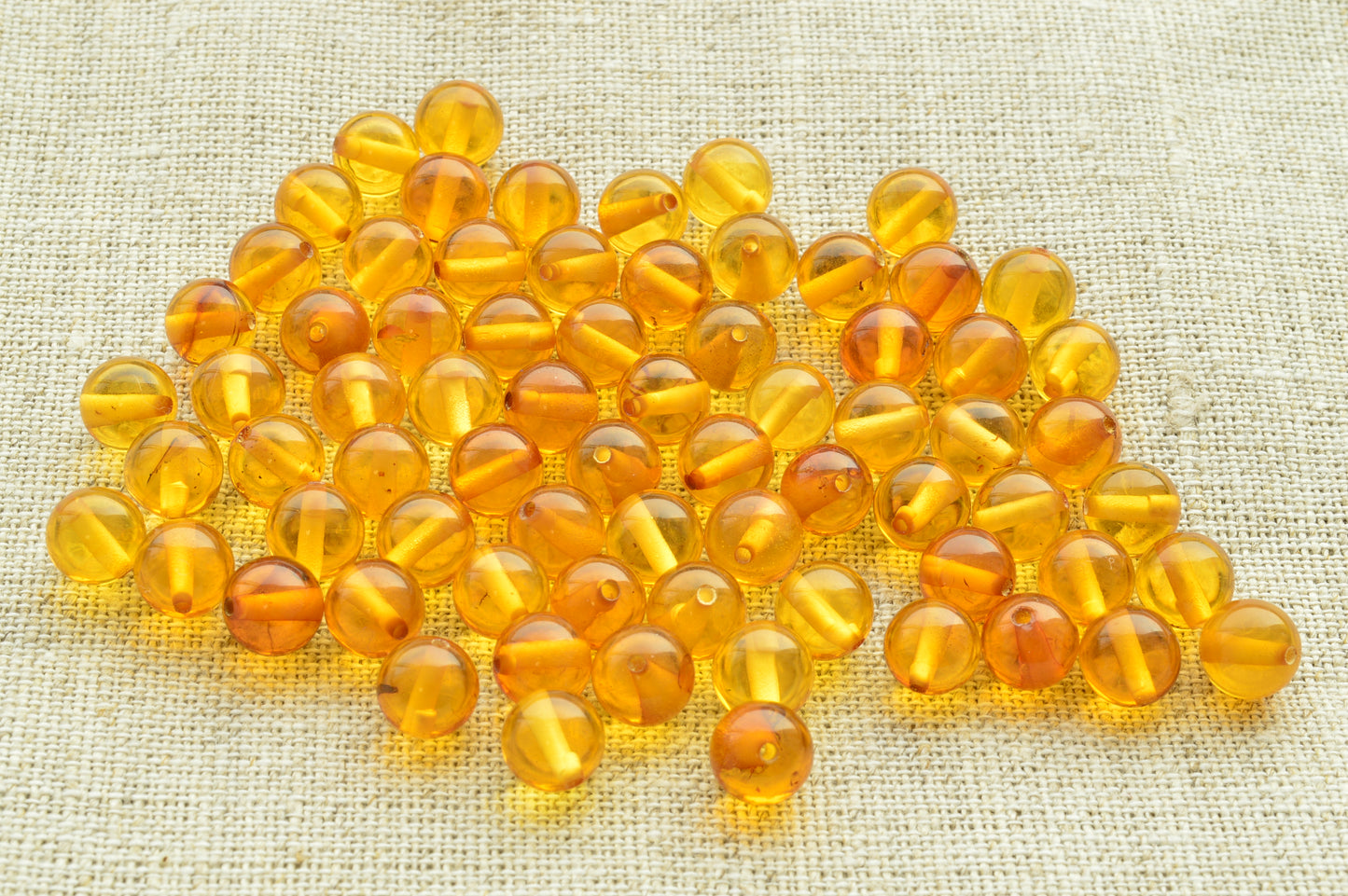 Natural baltic amber Orange beads on a textured beige fabric background