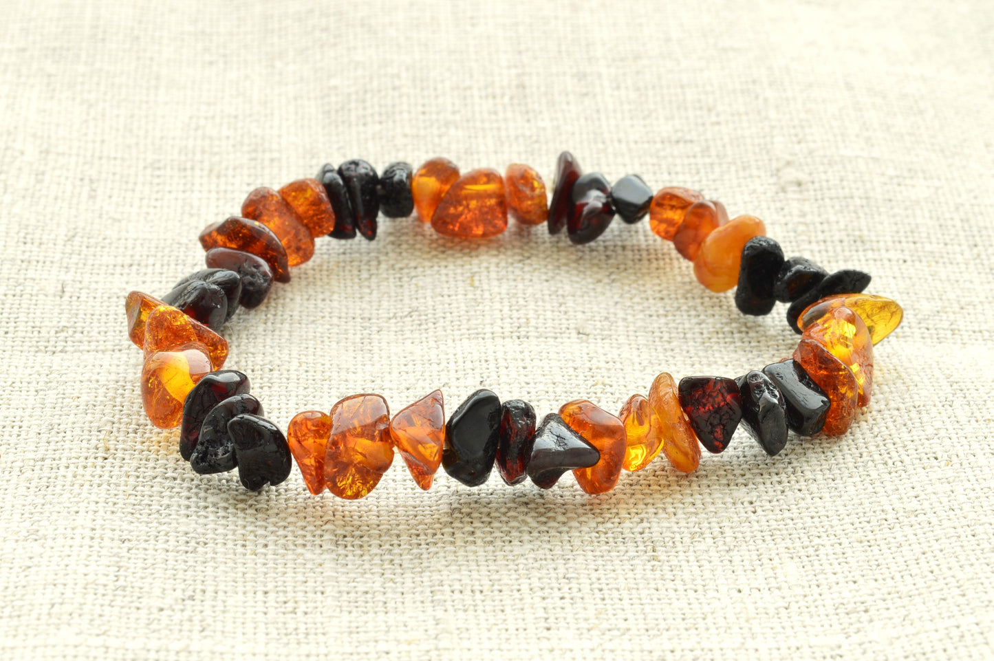 Bracelet made of brown and black  amber on a textured beige background