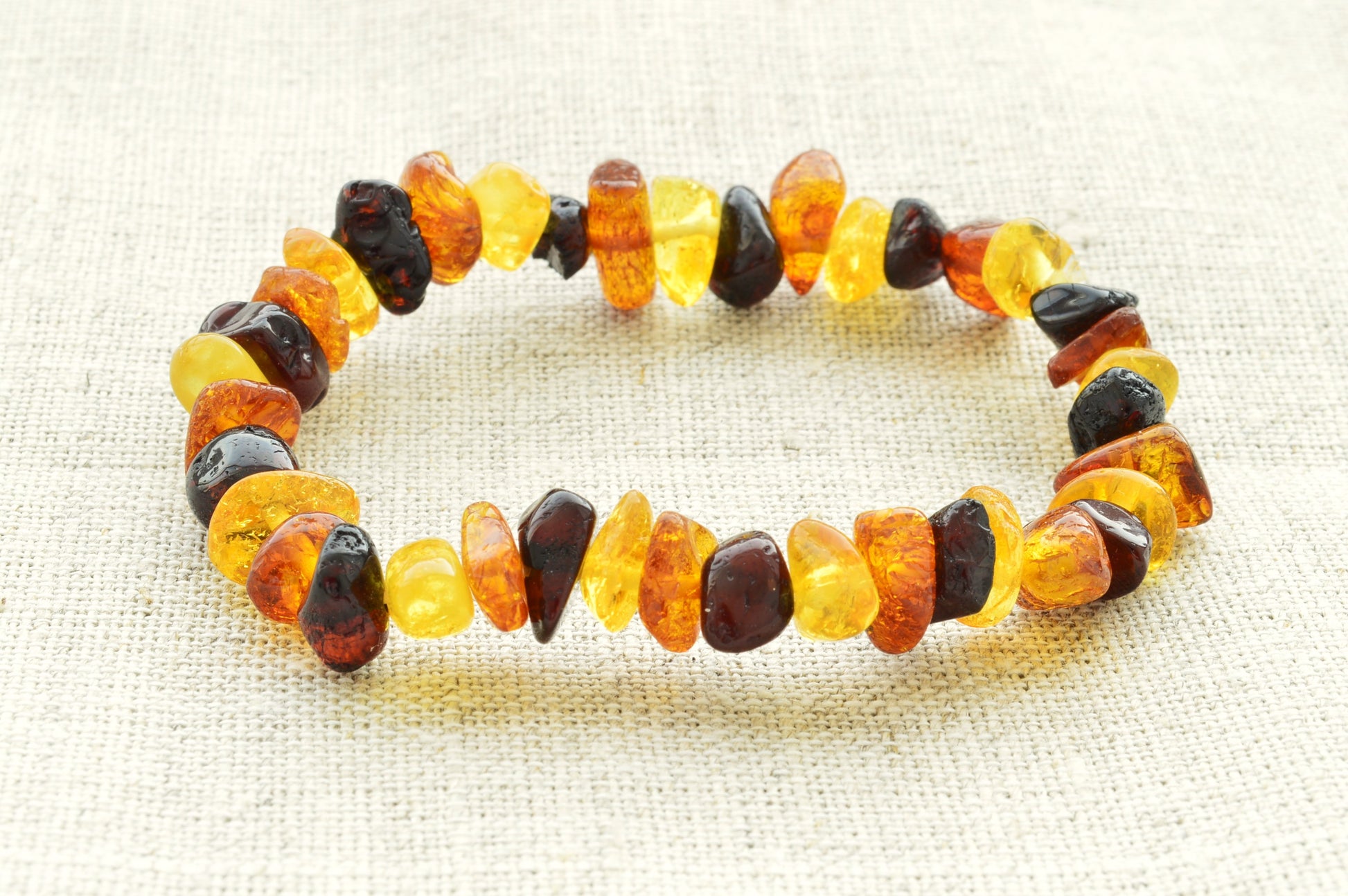 Multicolored amber bracelet on a textured beige background