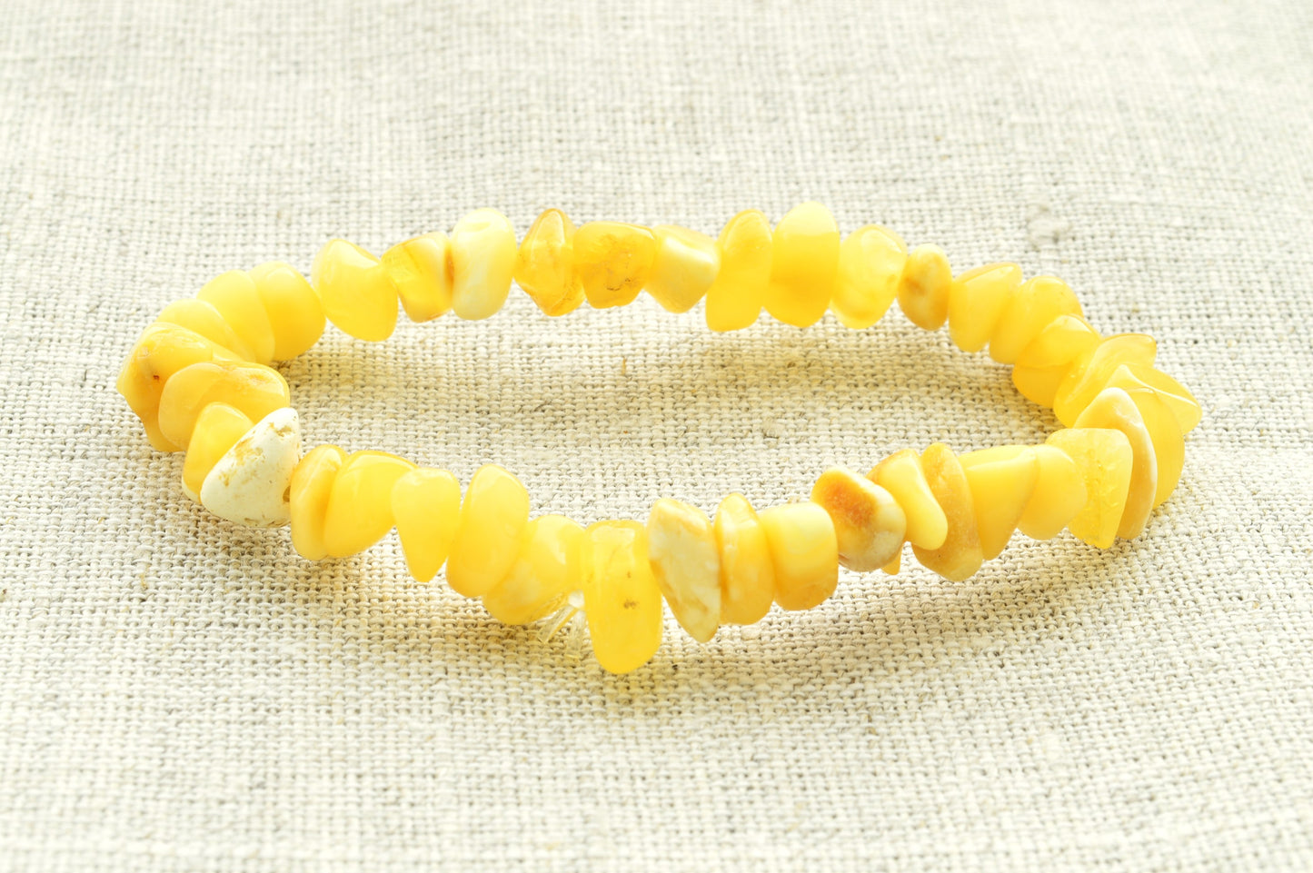 Yellow beaded natural baltic amber bracelet on a textured beige background