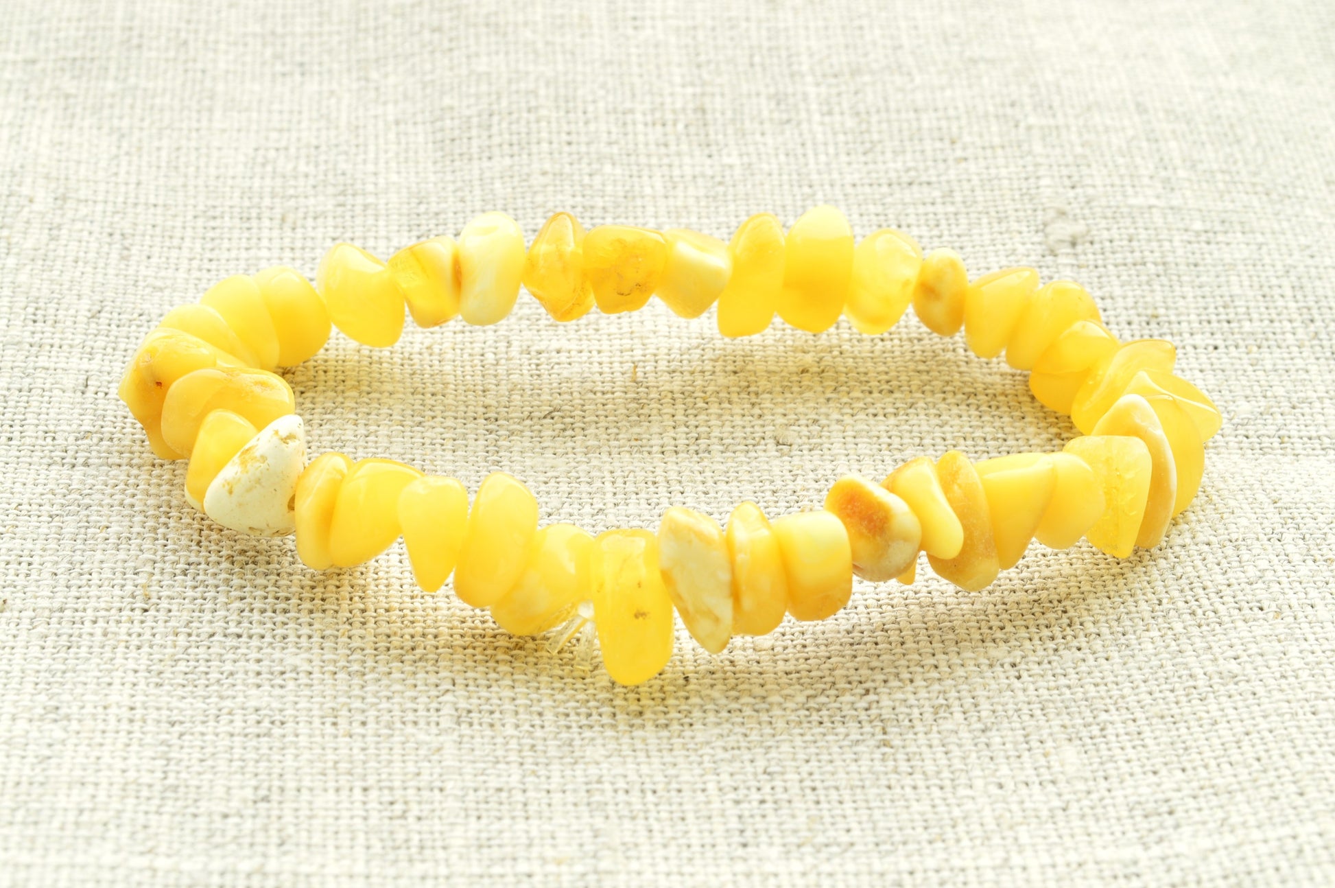 Yellow beaded natural baltic amber bracelet on a textured beige background
