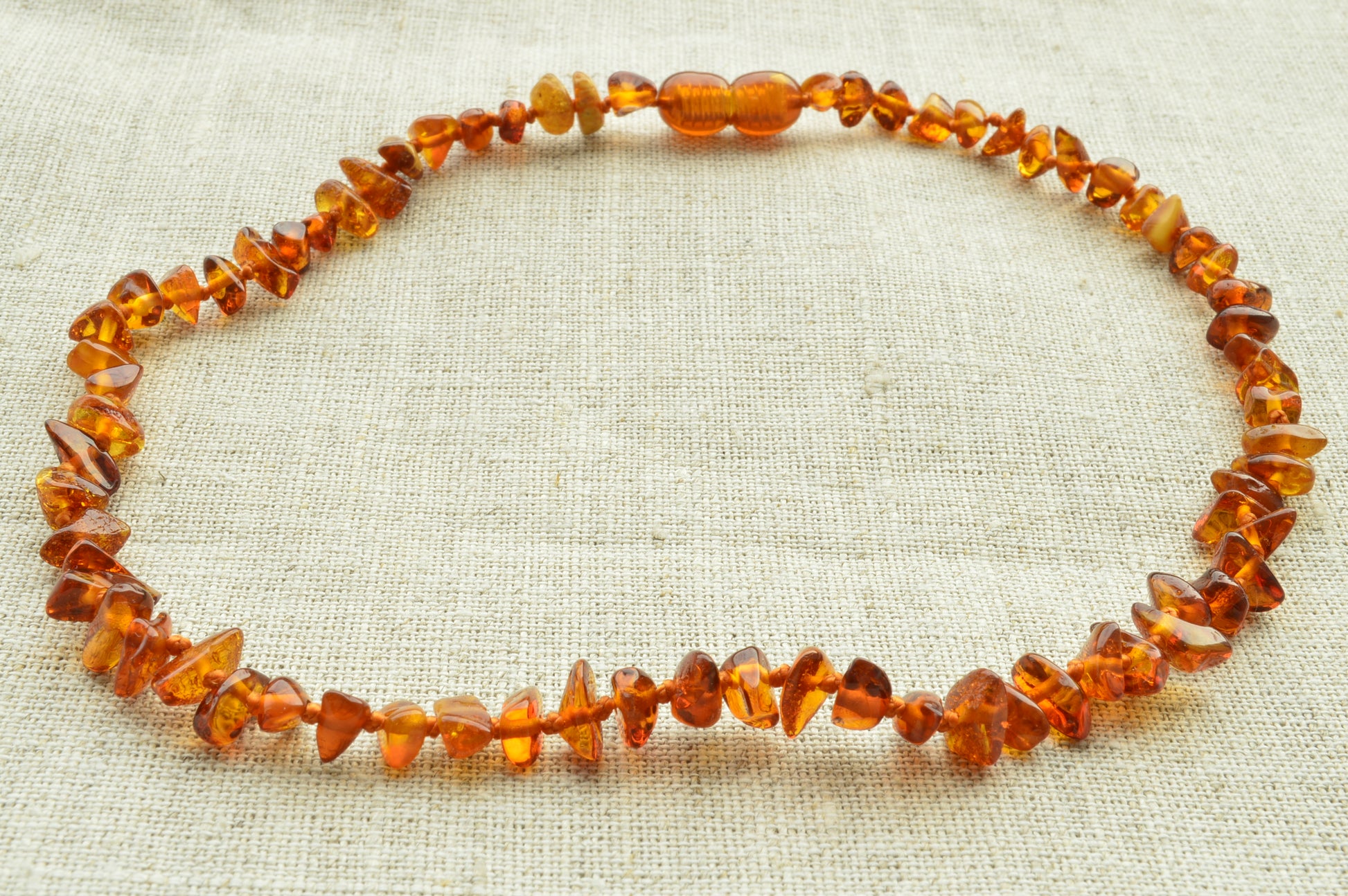 Carnelian beaded necklace on a textured beige fabric background