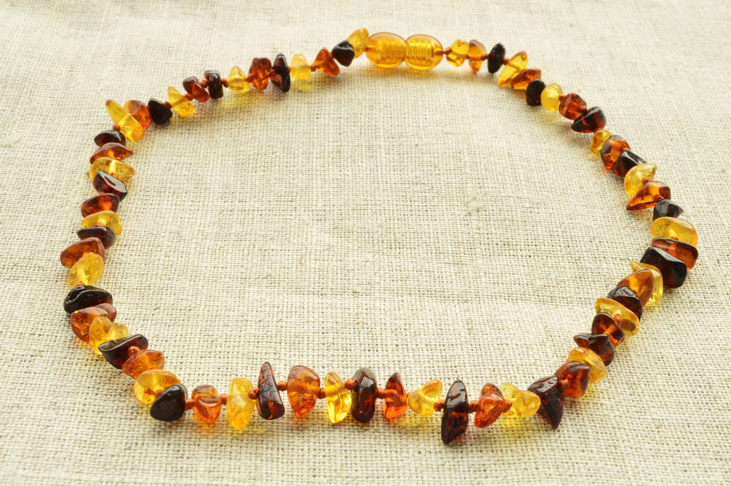 Necklace made of multicolored amber beads on a textured beige background
