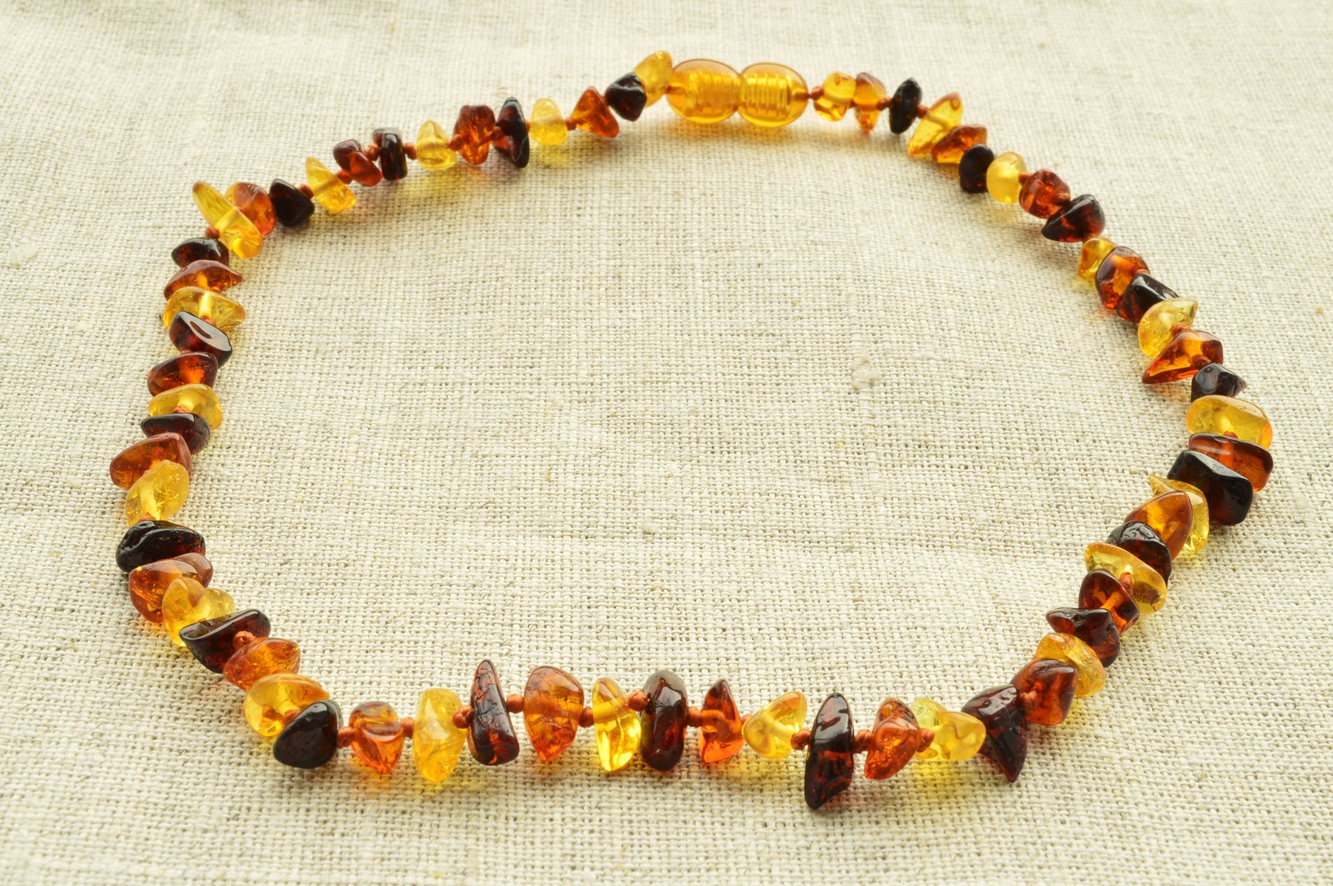 Necklace made of multicolored amber beads on a textured beige background