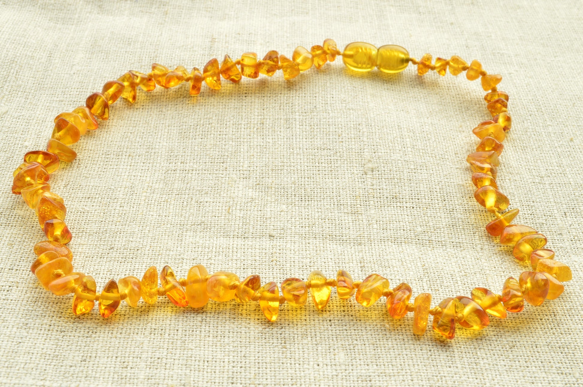 Yellow beaded necklace on a textured beige fabric background
