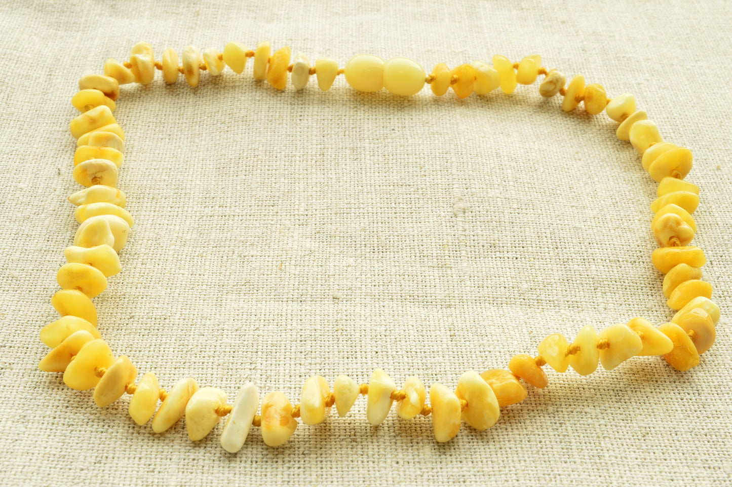 Necklace made of yellow and white beads on a textured beige background