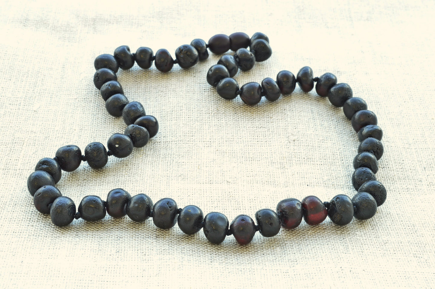 Necklace with dark beads on a beige fabric background