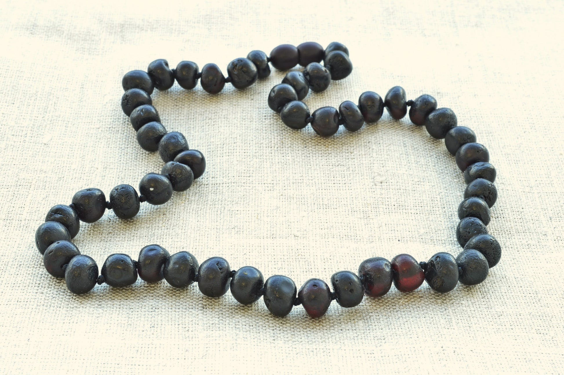 Necklace with dark beads on a beige fabric background