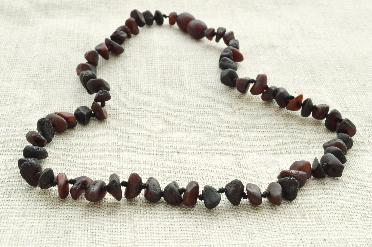 Necklace made of dark brown beads on a light fabric background
