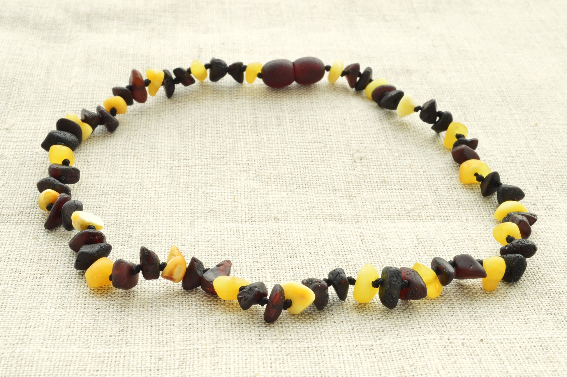 Necklace with multicolored beads on a beige fabric background