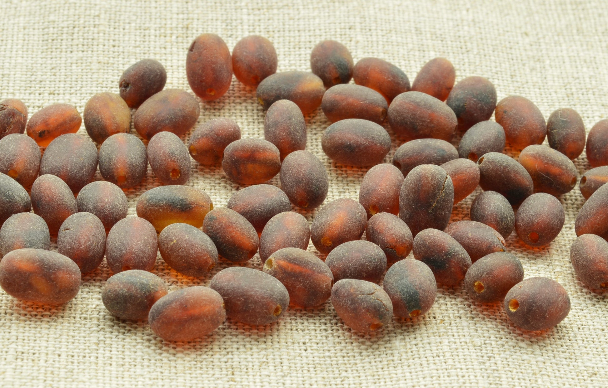 Brown amber beads scattered on a textured fabric surface