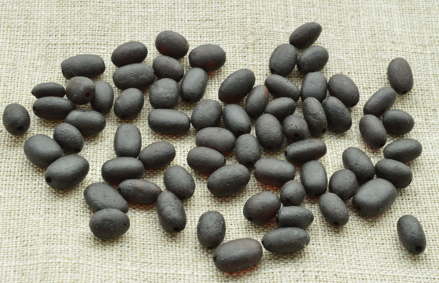 natural baltic amber loose beads oblong raw unpolished on a textured beige surface