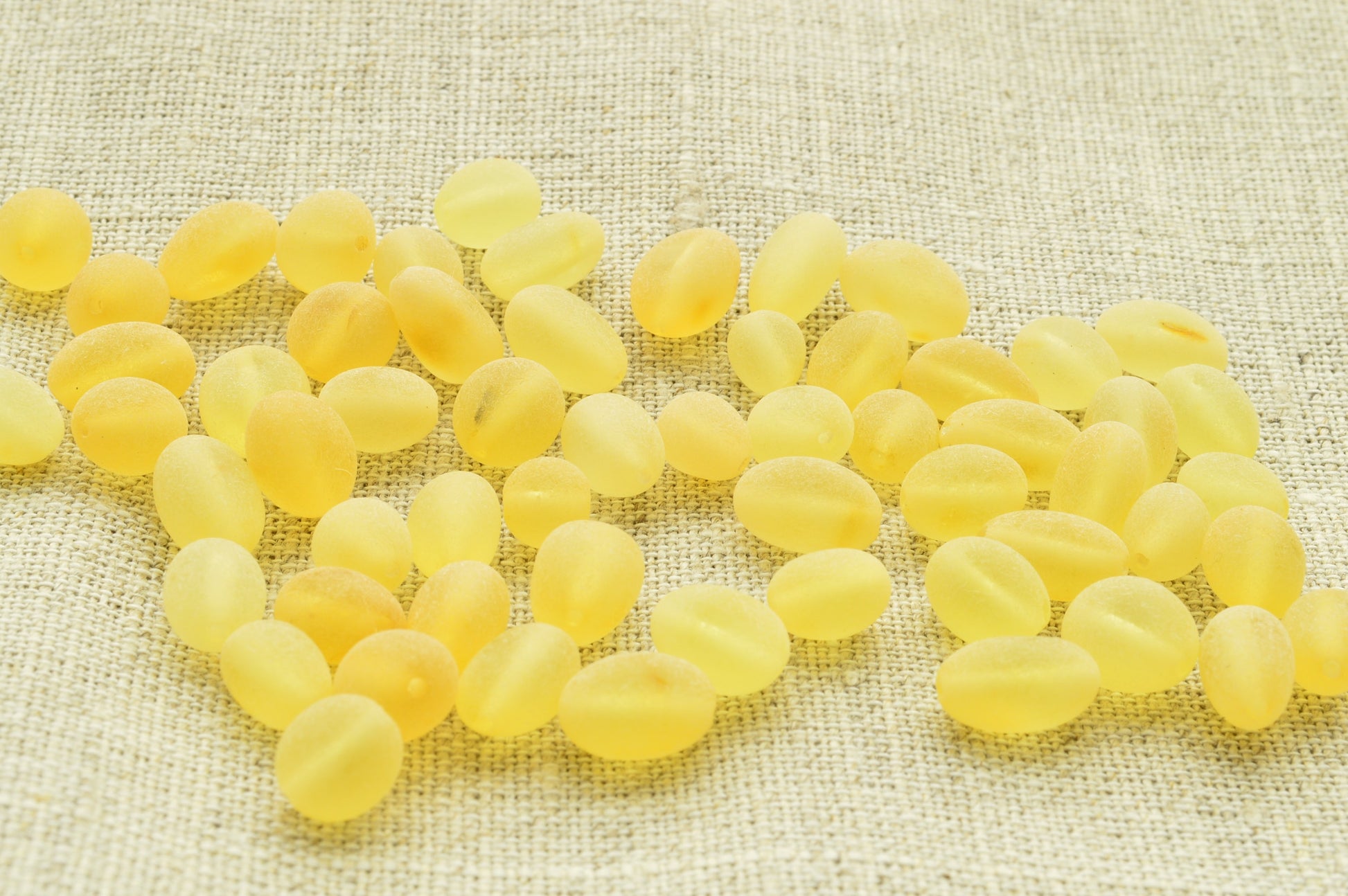 Yellow amber beads scattered on a textured beige fabric background