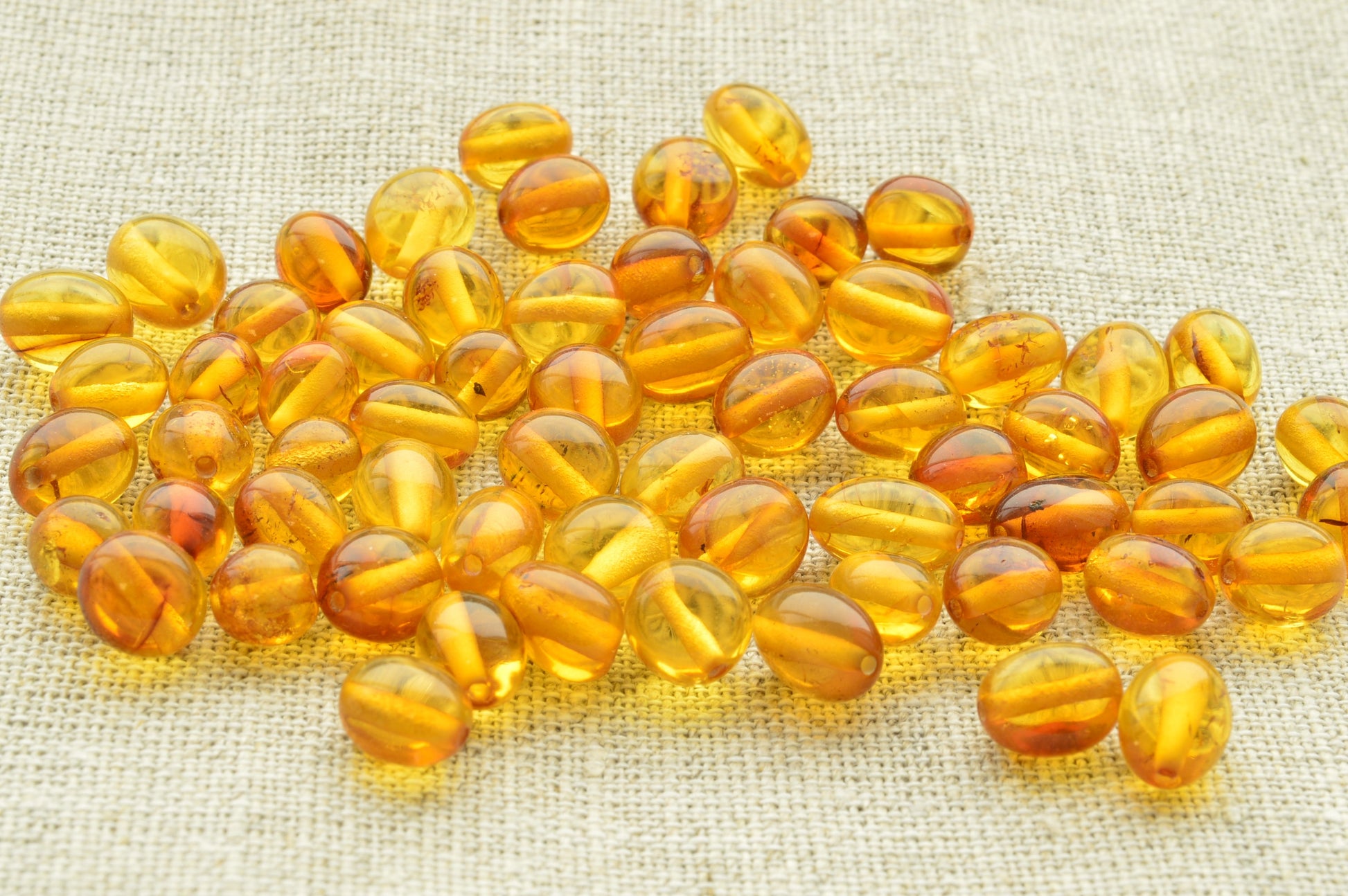 Amber-colored beads on a textured fabric background