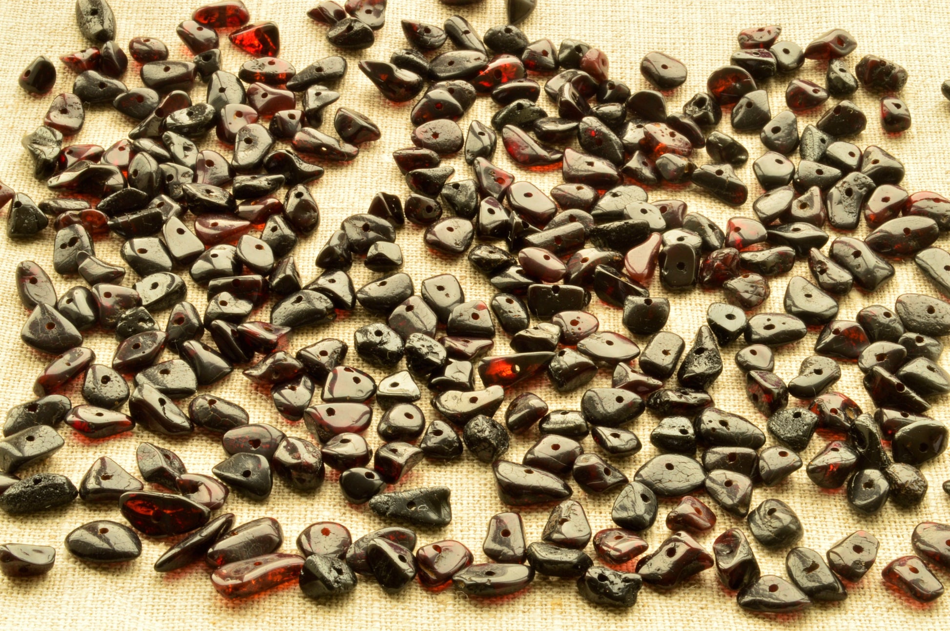 Collection of dark natural baltic amber polished chip beads on a textured surface