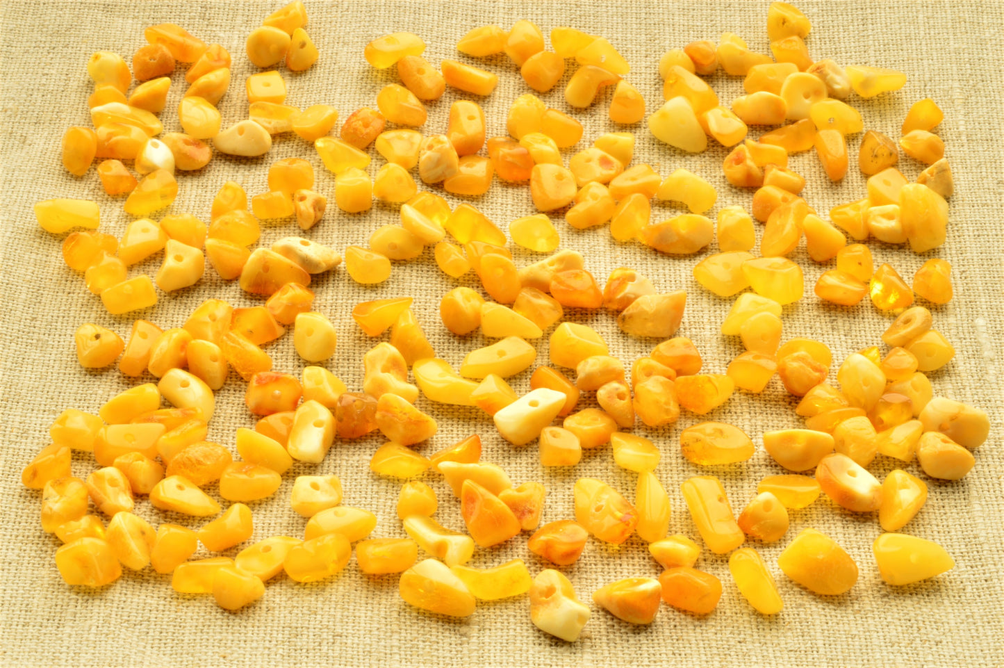 natural baltic amber polished chip beads on a textured beige fabric background