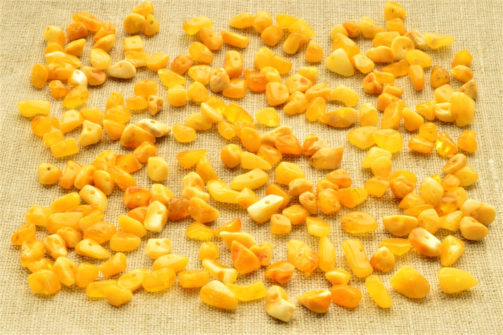 natural baltic amber polished chip beads on a textured beige fabric background