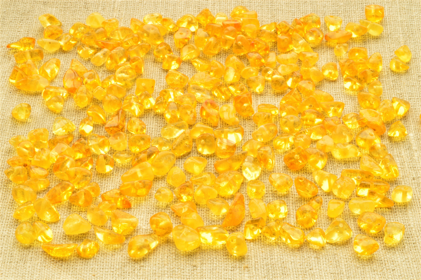 natural baltic amber polished chip beads on a textured beige fabric background