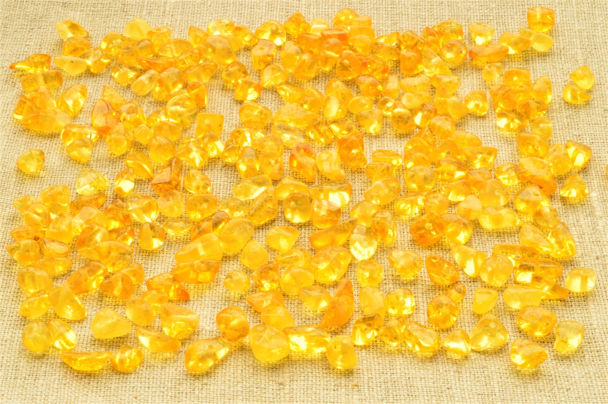 natural baltic amber polished chip beads on a textured beige fabric background