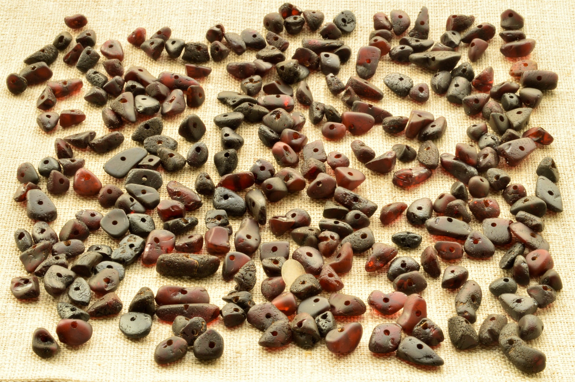 Collection of ancient natural baltic amber raw unpolished chip beads on a textured fabric background