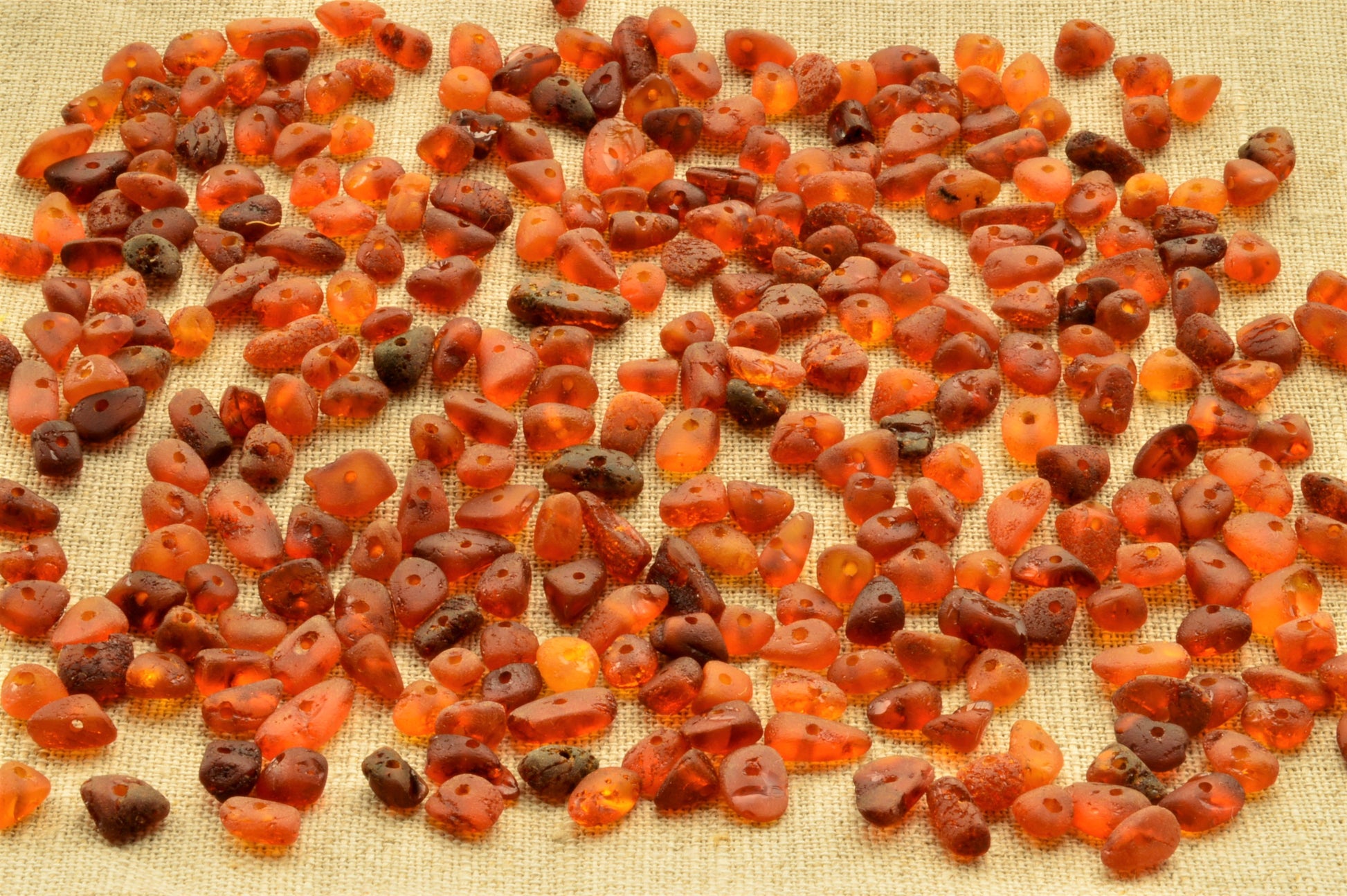 Scattered amber beads on a textured fabric background