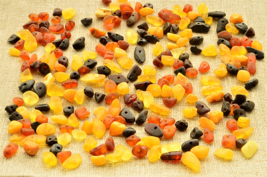 Assorted natural baltic amber raw unpolished chip beads on a textured surface