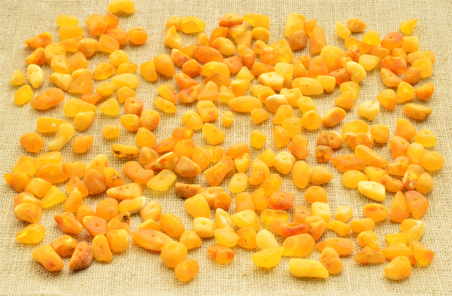 Yellow and natural baltic amber raw unpolished chip beads on a textured beige background